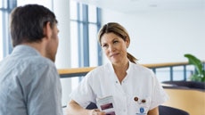 Sykepleier som snakker med mannlig pasient