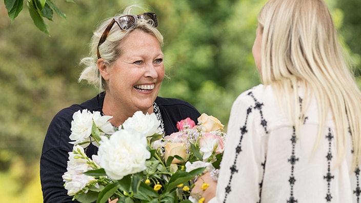 kvinne med blomsterbukett snakker med venninne