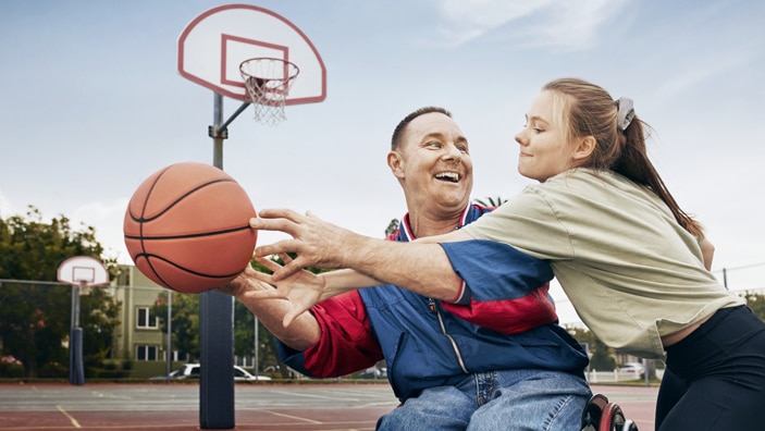 Mann i rullestol spiller basket med jente