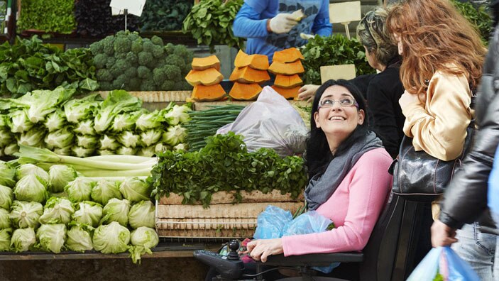 Kvinne i rullestol på grønnsaksmarked