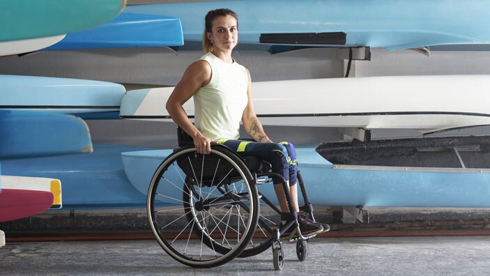 Kvinne i rullestol foran robåter